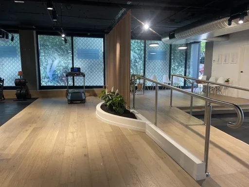The open floor of an Align Health Collective clinic: timber boards, a treadmill against the window and framed foot anatomy prints on the far wall.